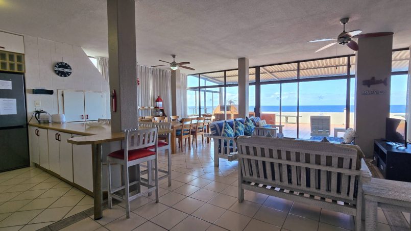 The bright open-plan lounge and kitchen with large windows overlooking the Indian Ocean at C Front 11