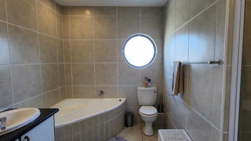 Modern en suite bathroom with a corner bath and a shower at Indigo Bay 25 self-catering unit