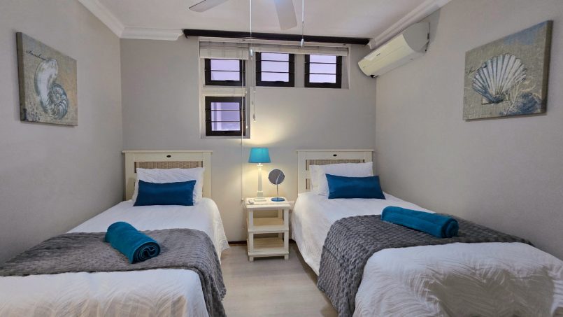 Third bedroom with two singles, air‑conditioning and ceiling fan