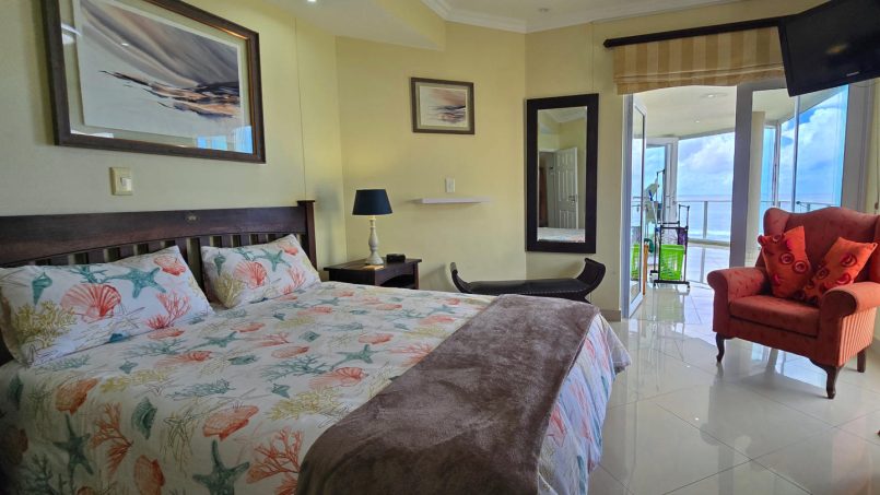 The main bedroom at Lucien Sands 501, with a sea view and doors to the patio.